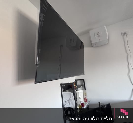 טלוויזיה מותקנת על הקיר עם מדף מתחת